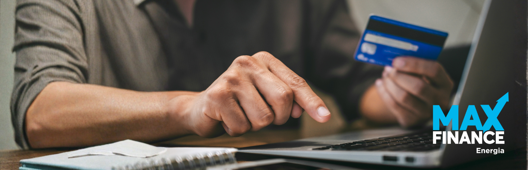 Banner da MaxFinance Energia com foco em crédito pessoal. Mostra uma pessoa a utilizar um computador portátil enquanto segura um cartão bancário, simbolizando operações financeiras online e gestão de crédito digital. O logótipo da MaxFinance Energia aparece no canto inferior direito.