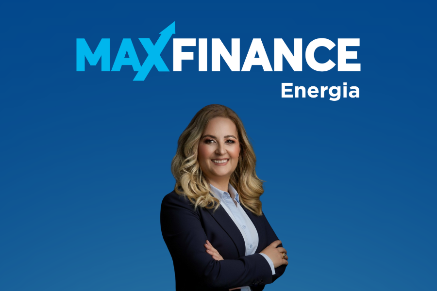 Banner corporativo da MaxFinance Energia com fundo azul e logótipo da marca no topo. Abaixo, uma mulher de cabelo loiro e comprido, vestida com blazer azul-escuro e camisa clara, sorri com os braços cruzados, transmitindo confiança e profissionalismo.